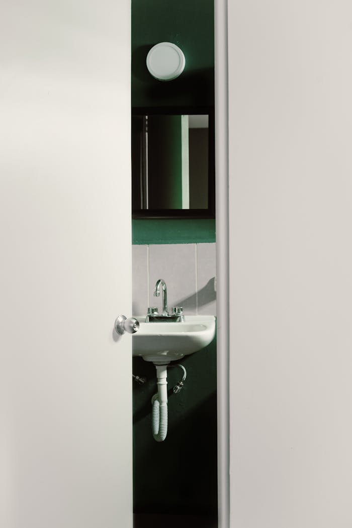 Contemporary bathroom interior with a partially open door, revealing a sleek and modern sink design.